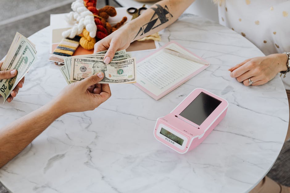Close-up of hands exchanging US dollars over a marble table with a card reader.