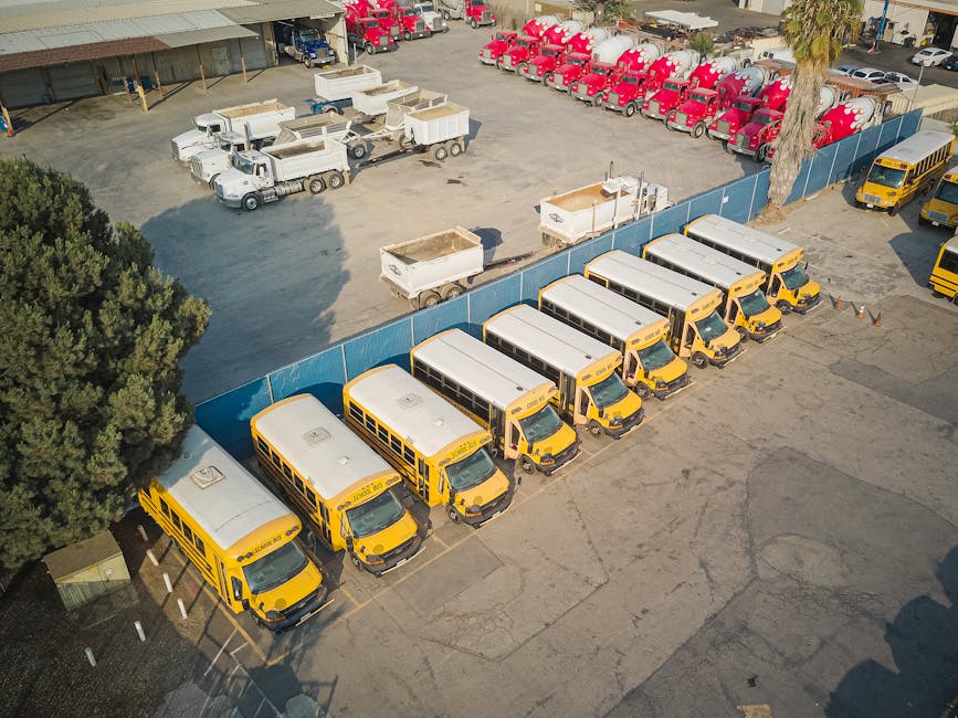 Aerial view of school buses and trucks parked in an industrial lot.