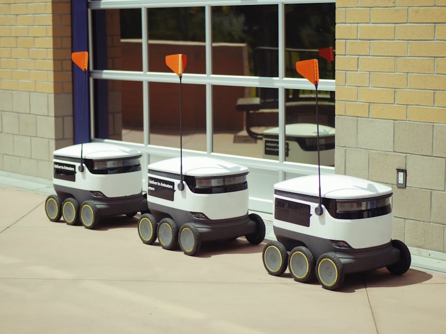 Three autonomous delivery robots parked outside a building, showcasing modern technology.